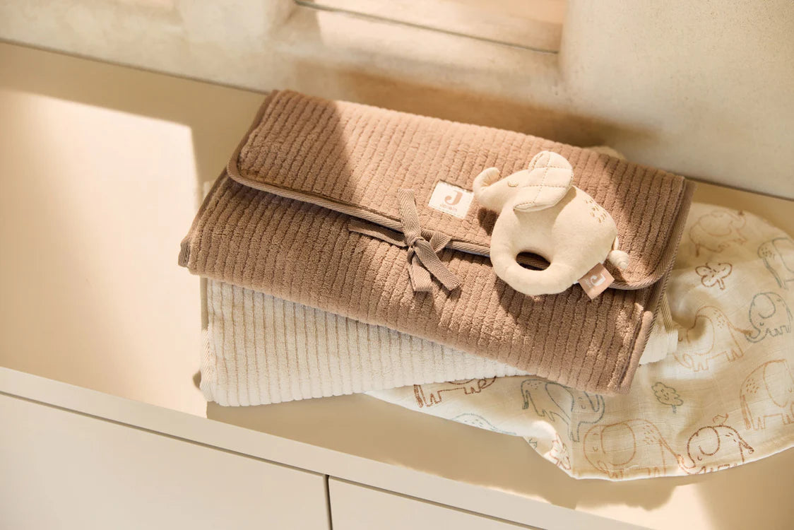 Tapis à langer nomade en tissu côtelé taupe avec intérieur feuillage. Léger, pliable et pratique avec poches intégrées. Idéal pour les sorties avec bébé.