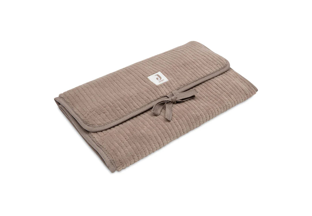 Tapis à langer nomade en tissu côtelé taupe avec intérieur feuillage. Léger, pliable et pratique avec poches intégrées. Idéal pour les sorties avec bébé.