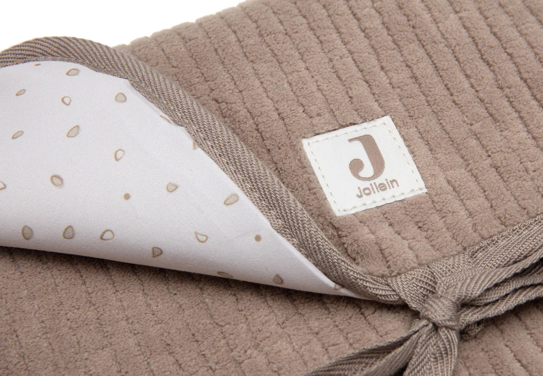 Tapis à langer nomade en tissu côtelé taupe avec intérieur feuillage. Léger, pliable et pratique avec poches intégrées. Idéal pour les sorties avec bébé.