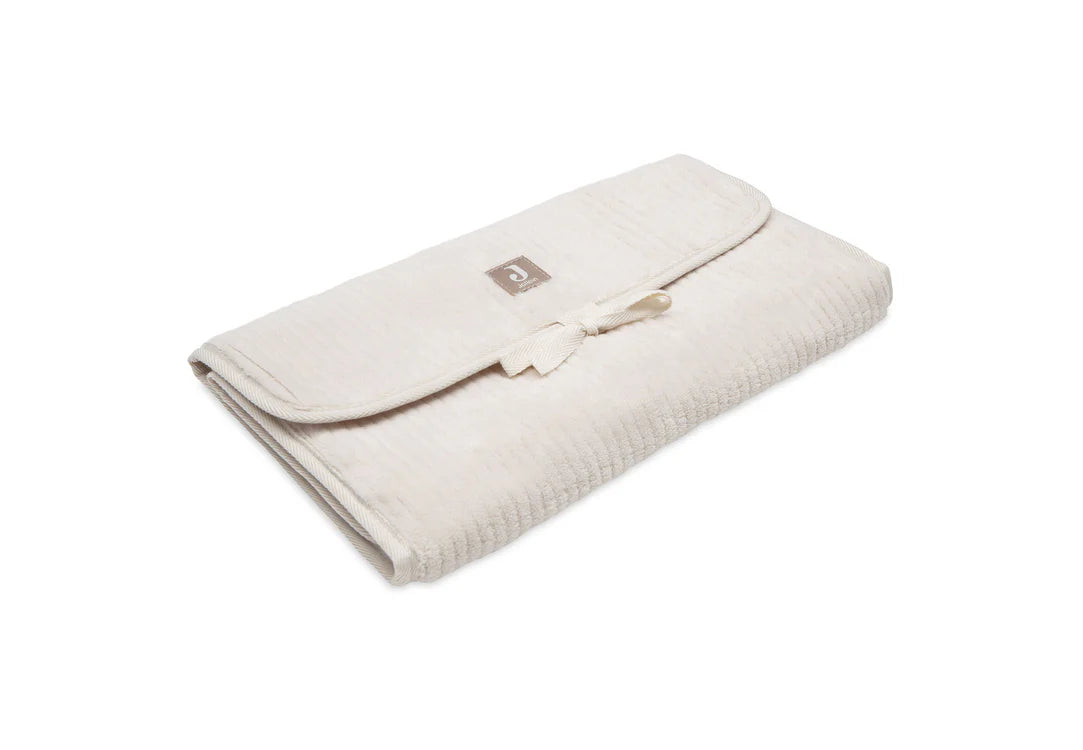 Tapis à langer nomade en tissu côtelé beige avec intérieur feuillage. Léger, pliable et pratique avec poches intégrées. Idéal pour les sorties avec bébé.