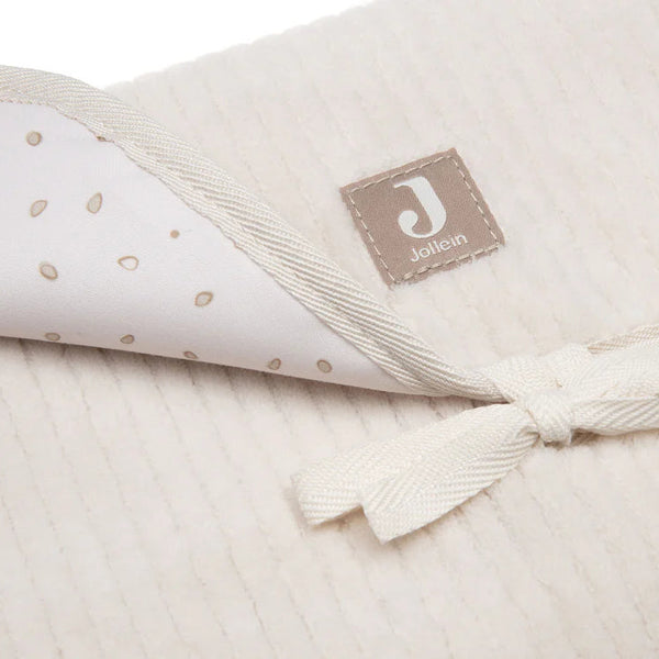 Tapis à langer nomade en tissu côtelé beige avec intérieur feuillage. Léger, pliable et pratique avec poches intégrées. Idéal pour les sorties avec bébé.