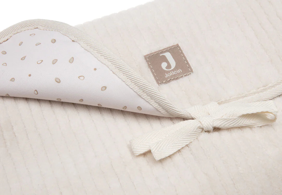 Tapis à langer nomade en tissu côtelé beige avec intérieur feuillage. Léger, pliable et pratique avec poches intégrées. Idéal pour les sorties avec bébé.