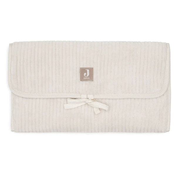 Tapis à langer nomade en tissu côtelé beige avec intérieur feuillage. Léger, pliable et pratique avec poches intégrées. Idéal pour les sorties avec bébé.
