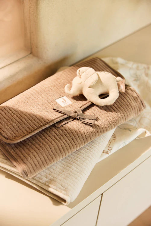 Tapis à langer nomade en tissu côtelé taupe avec intérieur feuillage. Léger, pliable et pratique avec poches intégrées. Idéal pour les sorties avec bébé.