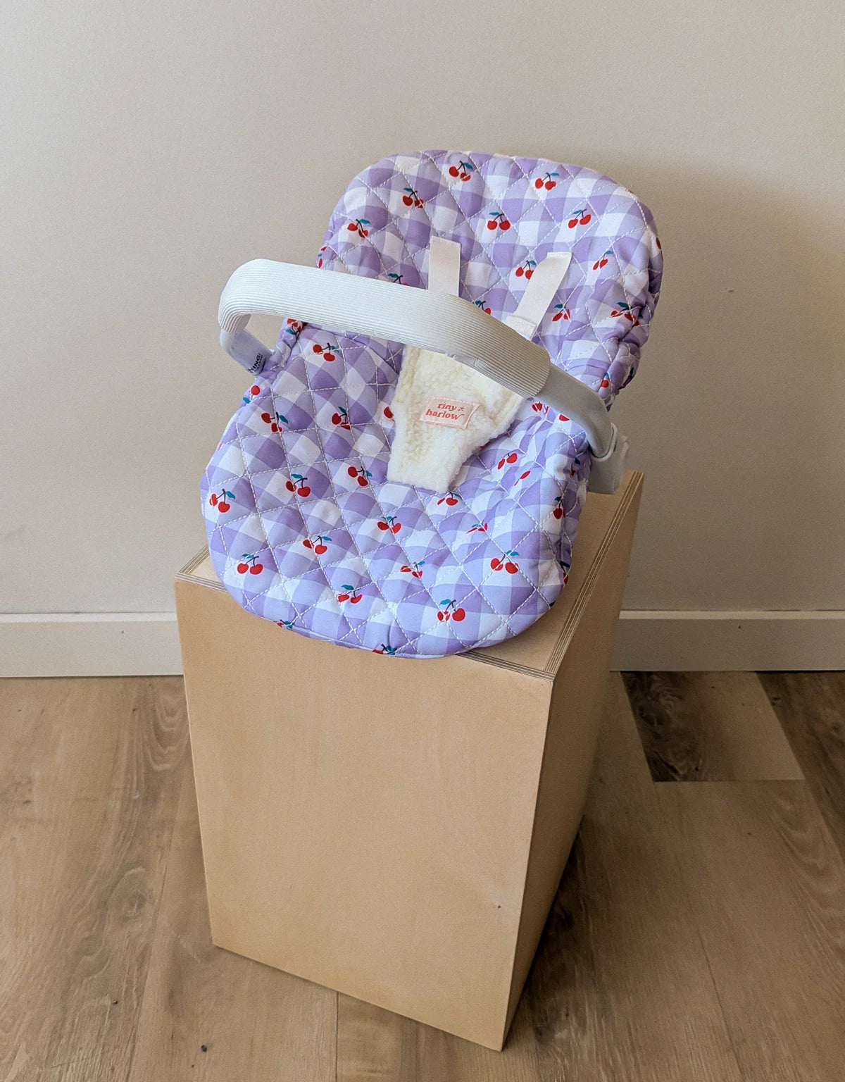 Coquille Tiny Harlow Vichy lilas et cerise pour transporter votre poupée partout. Poignée, sangles sécurisées et housse amovible lavable. Jouet d’imitation pour enfants dès 3 ans.