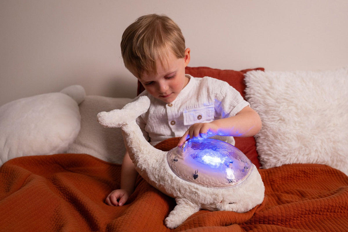 Veilleuse bébé Tranquil Whale™ blanche rechargeable : projections océaniques, bruits blancs, capteur de pleurs et minuterie. Idéale dès la naissance et parfaite en cadeau de naissance.