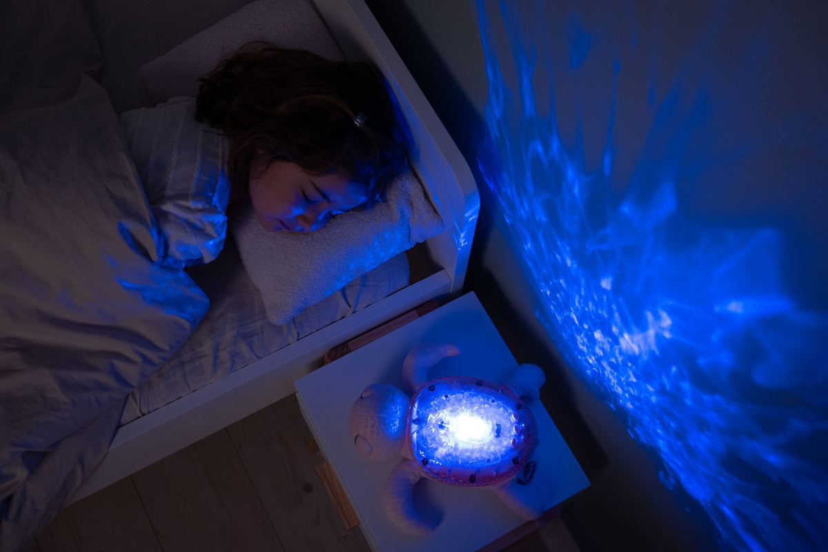 Veilleuse bébé Tranquil Turtle™ rose rechargeable : projections océaniques, bruits blancs, capteur de pleurs et minuterie. Idéale dès la naissance et parfaite en cadeau de naissance.