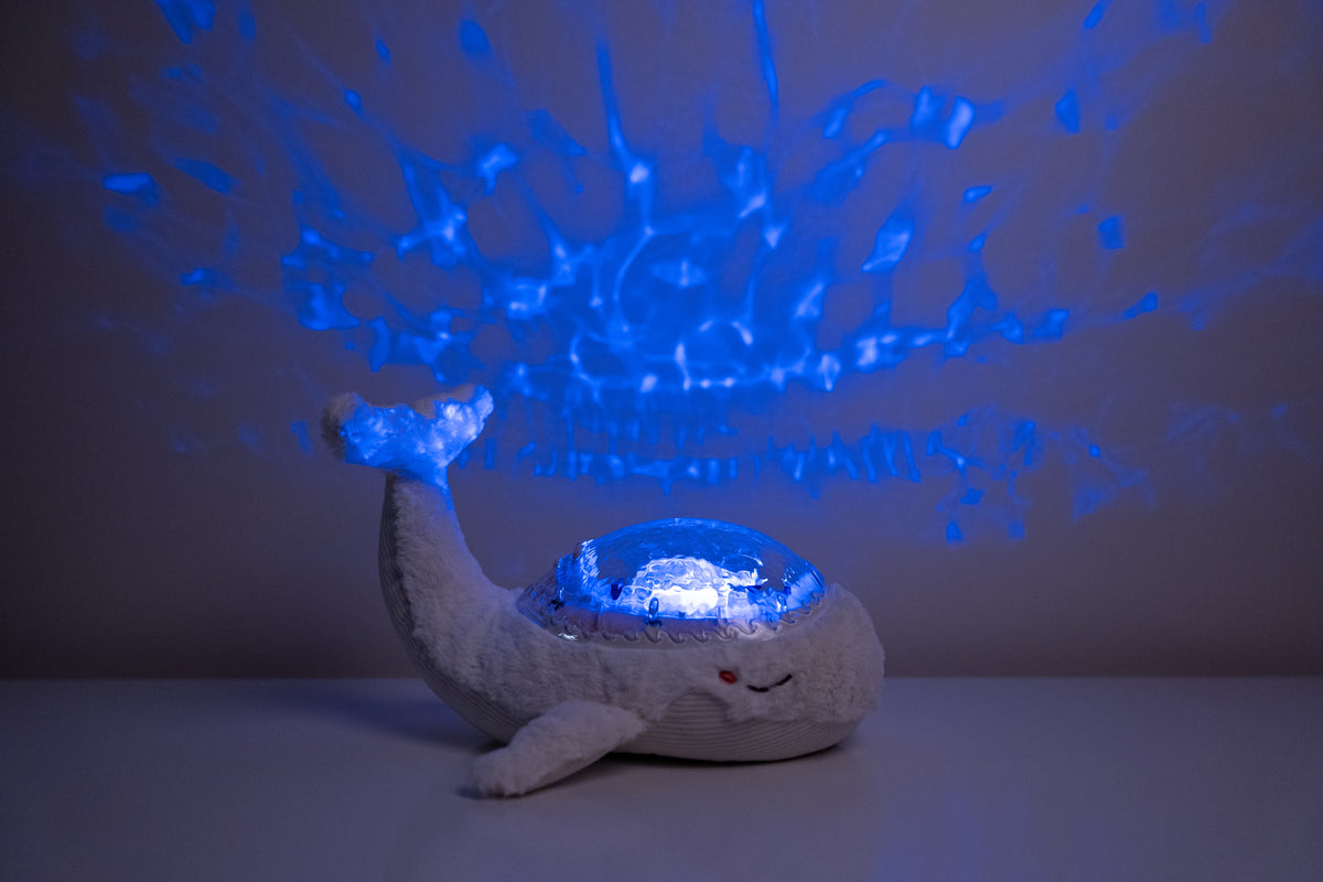 Veilleuse bébé Tranquil Whale™ blanche rechargeable : projections océaniques, bruits blancs, capteur de pleurs et minuterie. Idéale dès la naissance et parfaite en cadeau de naissance.