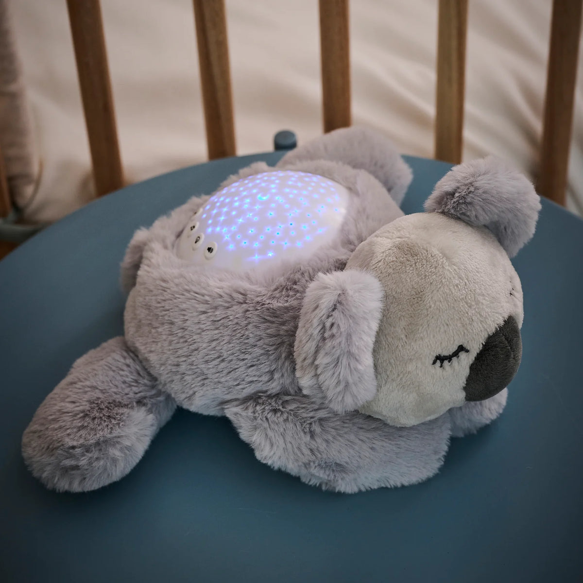 Veilleuse peluche pour bébé avec projection d’étoiles et sons relaxants. Timer 20 min, lumière douce et câline pour un sommeil paisible.